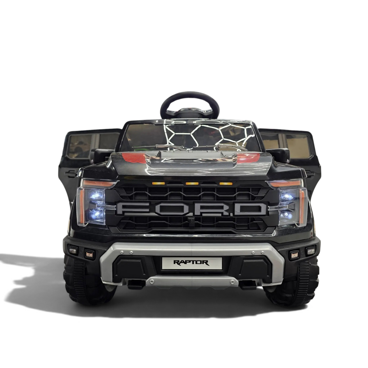 Voiture électrique enfant Petit Pilote Ford Raptor 12V noire avec calandre robuste et phares LED dans un showroom