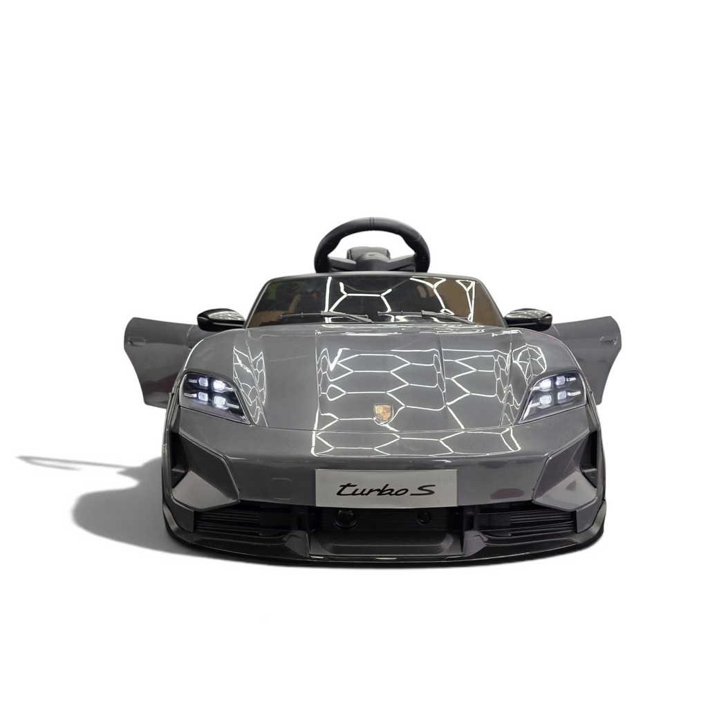 Voiture électrique pour enfant Petit Pilote Porsche Taycan grise avec portes ouvrantes et phares LED dans un showroom