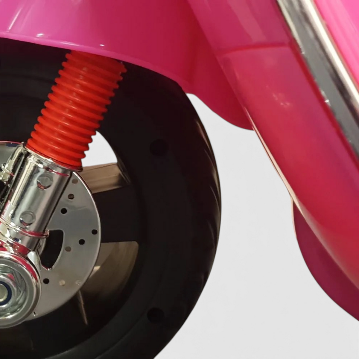 Gros plan sur la roue avant rose et la suspension chromée du scooter électrique pour enfant Vespa GTS par Petit Pilote
