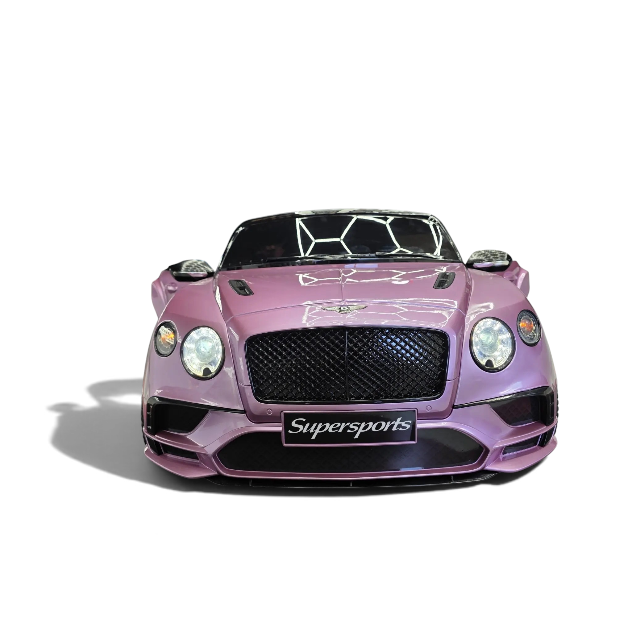 Voiture électrique enfant Odecare Bentley Continental rose métallisé avec phares allumés dans un showroom