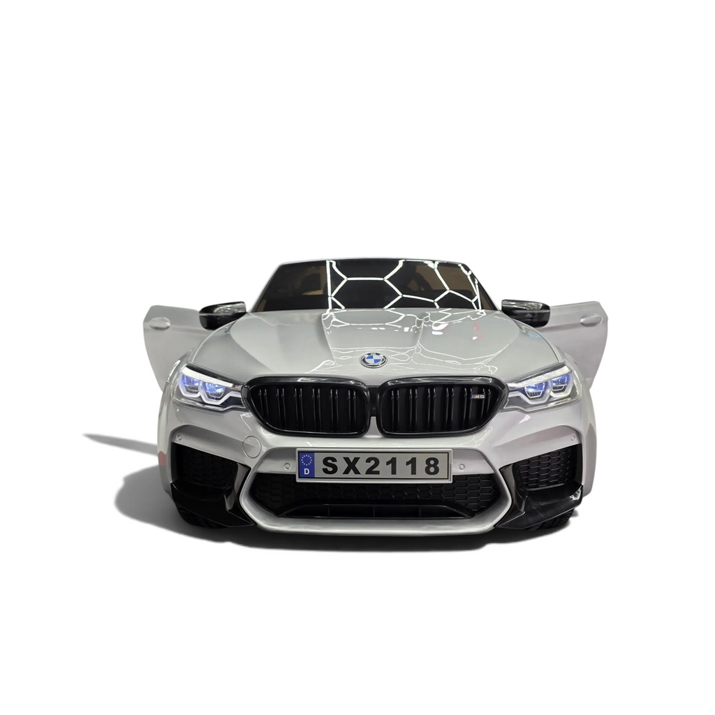 Voiture électrique enfant Odecare BMW M5 gris métallisé avec phares LED allumés dans un showroom