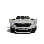 Voiture électrique enfant Odecare BMW M5 gris métallisé avec phares LED allumés dans un showroom