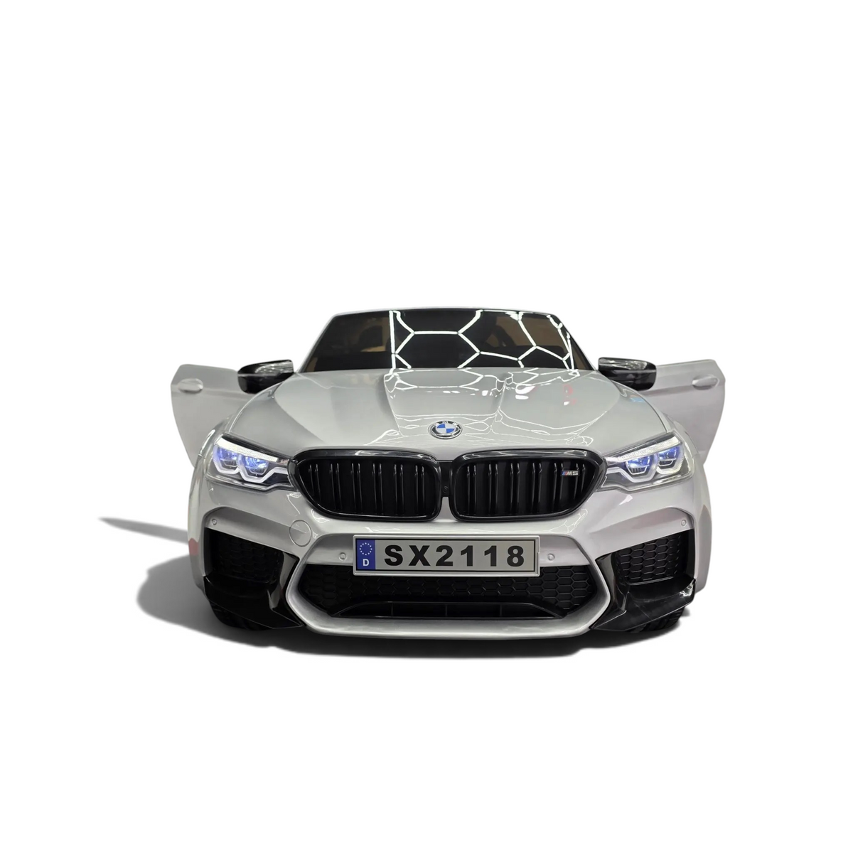 Voiture électrique enfant Odecare BMW M5 gris métallisé avec phares LED allumés dans un showroom