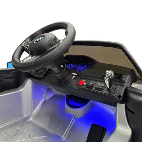 Intérieur de la voiture électrique enfant Odecare BMW M5 avec volant siglé, tableau de bord et éclairage LED bleu