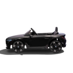 Voiture électrique pour enfant Petit Pilote BMW i4 noire métallisée, vue de profil avec roues sportives et siège en cuir