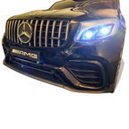 Gros plan sur la calandre et les phares LED allumés de la voiture électrique enfant Petit Pilote Mercedes GLC 63 AMG noire
