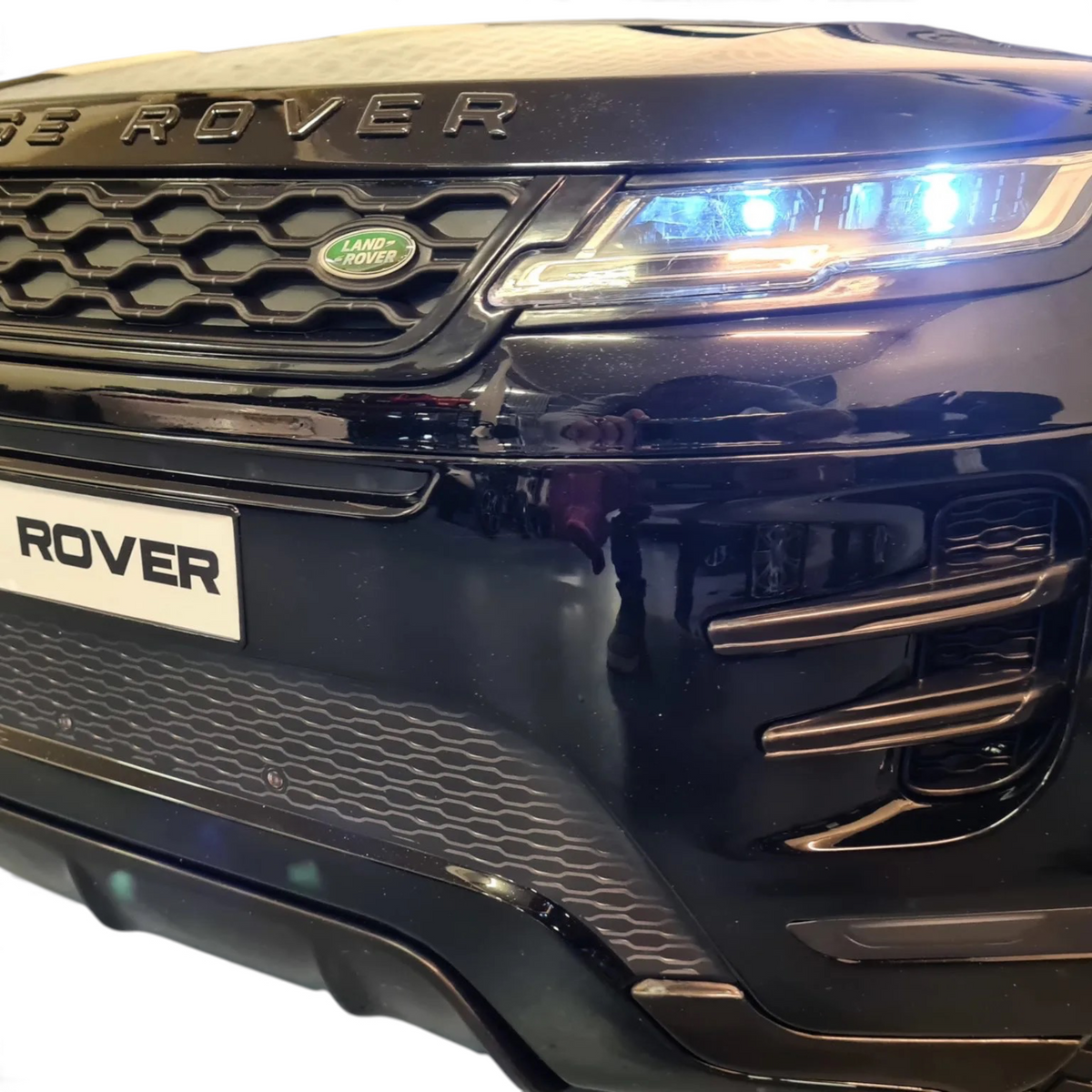 Gros plan sur la calandre et les phares LED d'une voiture électrique enfant Odecare Range Rover Evoque noir métallisé