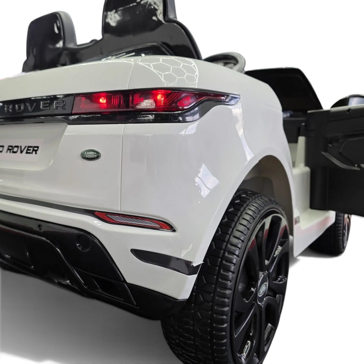 Vue arrière de la voiture électrique enfant Petit Pilote Range Rover Evoque blanche avec feux rouges et pneus en caoutchouc