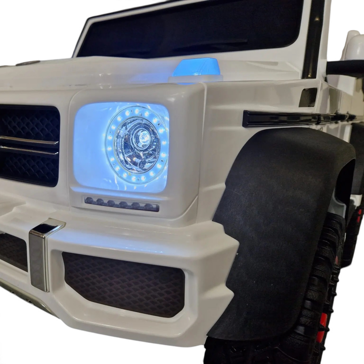 Gros plan sur la face avant blanche de la voiture électrique pour enfant Petit Pilote Mercedes G63 AMG avec phares LED